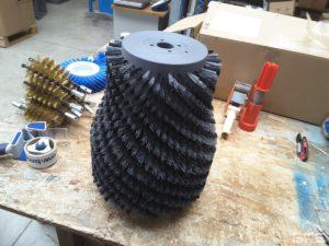 Brosse rotative cylindrique garnie de filaments pour le nettoyage des bouteilles de vin.