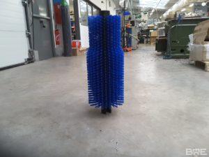 Une brosse rotative cylindrique avec un garnissage spécifique, conçue pour le nettoyage et le polissage des bouteilles dans une machine d'embouteillage.