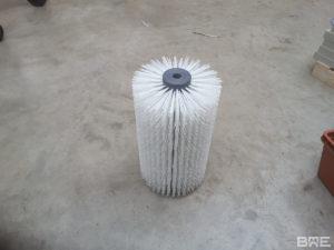 Une brosse rotative à poils longs est présentée, fixée sur un support métallique. Elle est utilisée pour le brossage des carottes dans le secteur agricole.