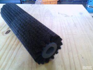 Brosse cylindrique à garnissage dense et souple utilisée pour le lustrage des pommes sur une ligne de conditionnement en agriculture. La brosse est constituée d'un corps cylindrique garni de filaments en fibres synthétiques, permettant un polissage doux et efficace des fruits.