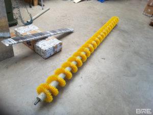Brosse hélicoïdale conçue pour le mélange et le transport de grains en milieu agricole. La brosse présente une structure en spirale avec des poils rigides, fixés sur un support central.