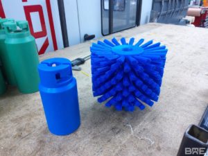 Une machine à frotter les fromages utilise une brosse cylindrique modulaire pour brosser une meule de Comté.
