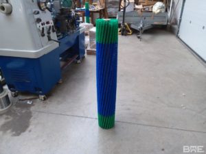 Une brosse rotative avec un garnissage en trois sections, conçue pour une utilisation sur un robot de nettoyage des panneaux solaires. La brosse est fixée à un support métallique et présente des poils souples et denses pour un nettoyage efficace des surfaces délicates.