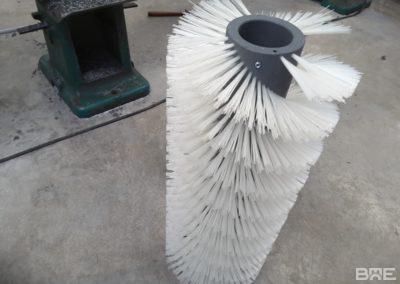Une brosse cylindrique hélicoïdale conçue pour le nettoyage efficace des bandes transporteuses dans les environnements industriels.